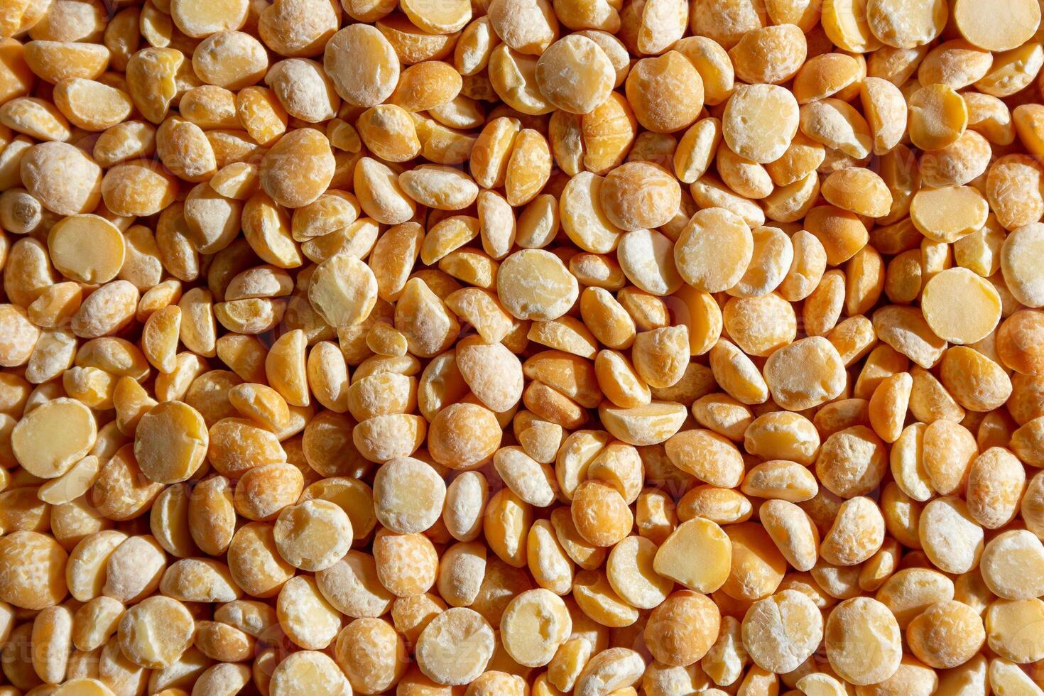 Uncooked Polished Split Peas Background. A Culinary Canvas of Dry Yellow Peas, Creating a Lively and Textured Background for Gourmet Cooking. Scattered Raw Polished Peas. Healthy Eating Ingredients photo