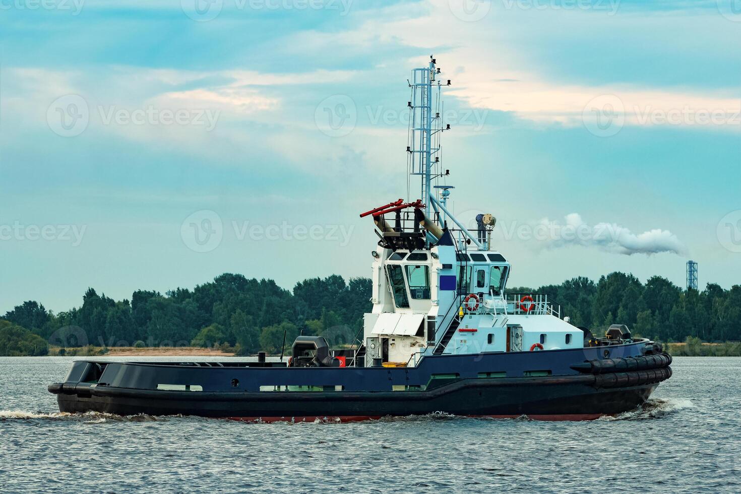 Black tug ship moving to the cargo terminal. Industrial service photo