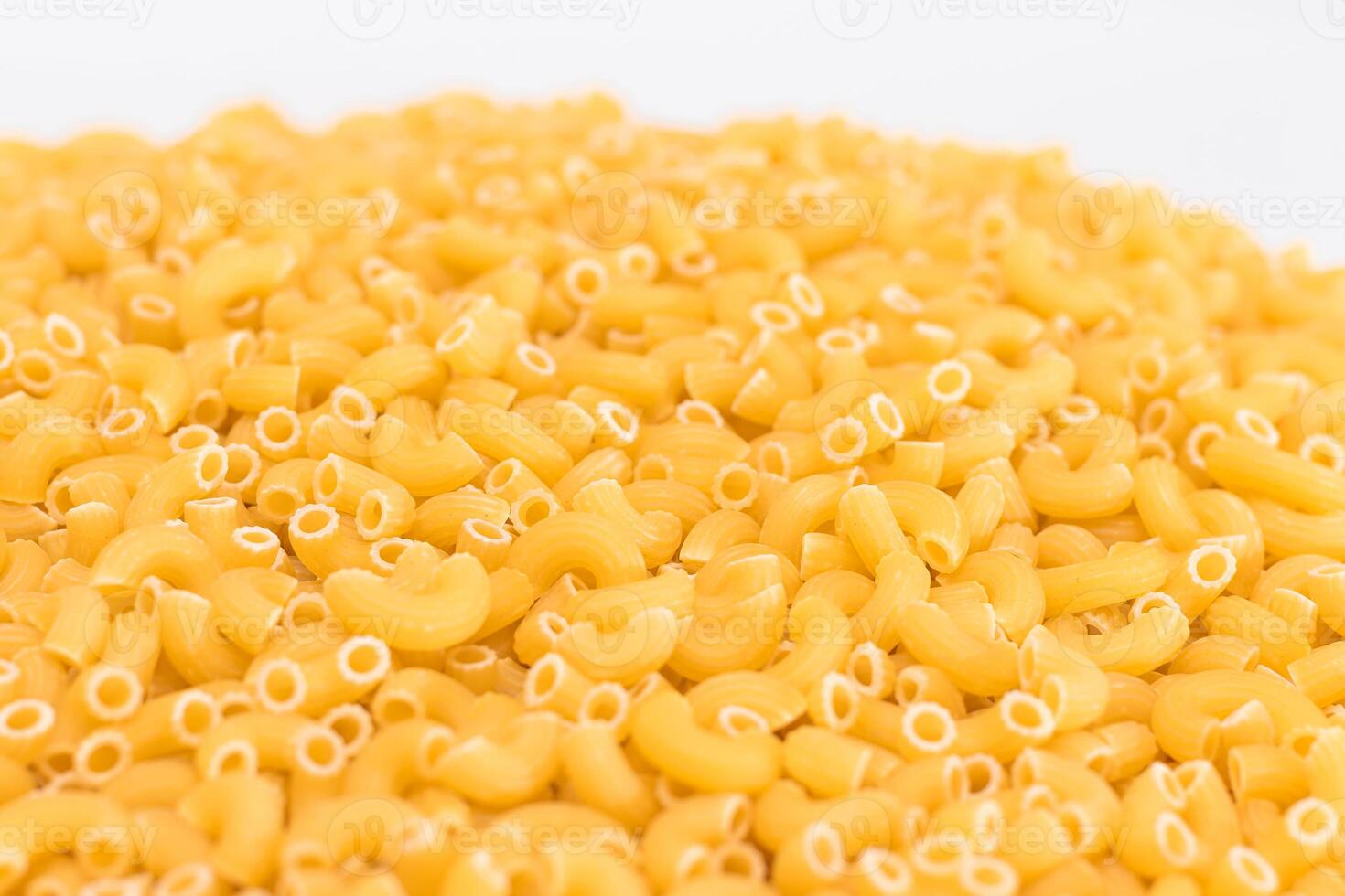 A Heap of Uncooked Chifferi Rigati Pasta on White Background. Fat and Unhealthy Food. Classic Dry Macaroni Texture. Italian Culture and Cuisine. Raw Pasta photo