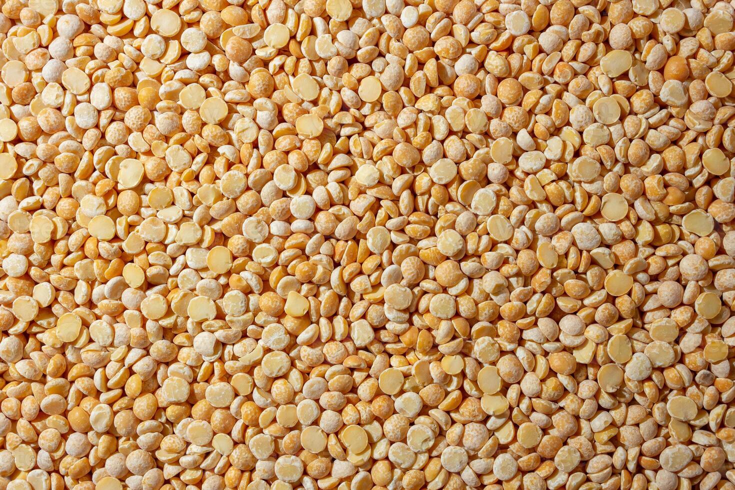 Uncooked Polished Split Peas Background. A Culinary Canvas of Dry Yellow Peas, Creating a Lively and Textured Background for Gourmet Cooking. Scattered Raw Polished Peas. Healthy Eating Ingredients photo