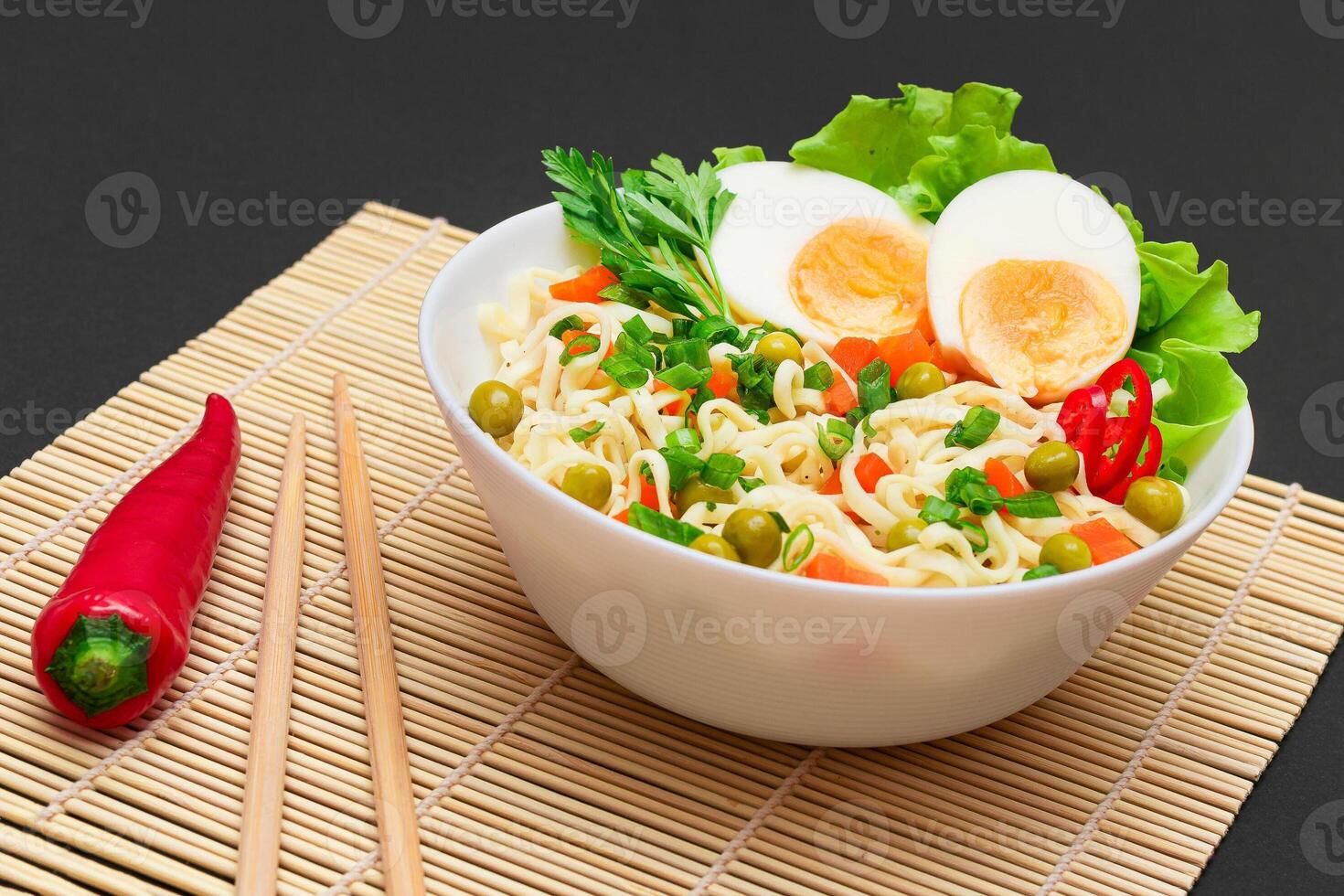 Beautiful Noodle Dish with Green Pea, Carrot, Eggs, Red Hot Pepper and Greens on Sushi Mat. Instant Noodles with Vegetables photo