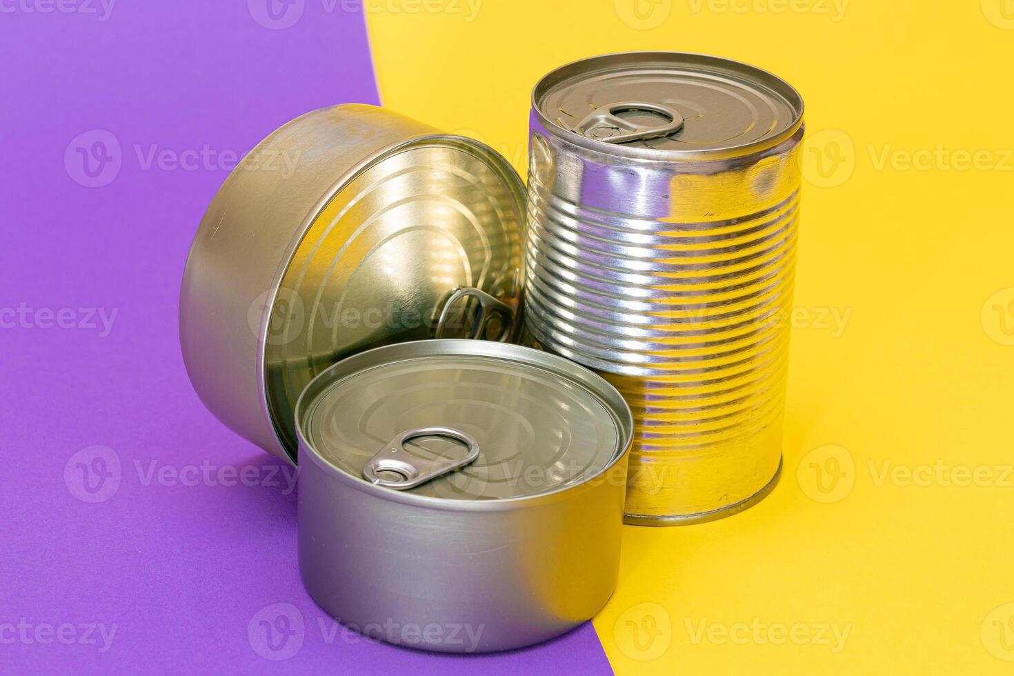 A Group of Stacked Tin Cans with Blank Edges on Split Yellow and Violet Background. Canned Food. Different Aluminum Cans for Safe and Long Term Storage of Food. Steel Sealed Food Storage Containers photo