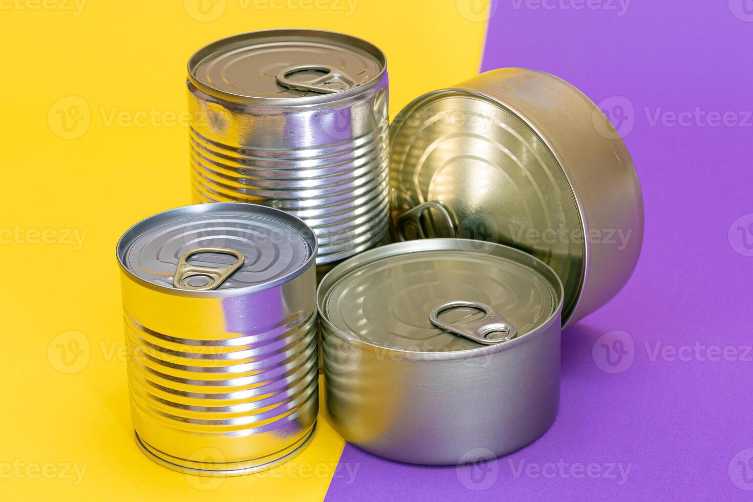 A Group of Stacked Tin Cans with Blank Edges on Split Yellow and Violet Background. Canned Food. Different Aluminum Cans for Safe and Long Term Storage of Food. Steel Sealed Food Storage Containers photo