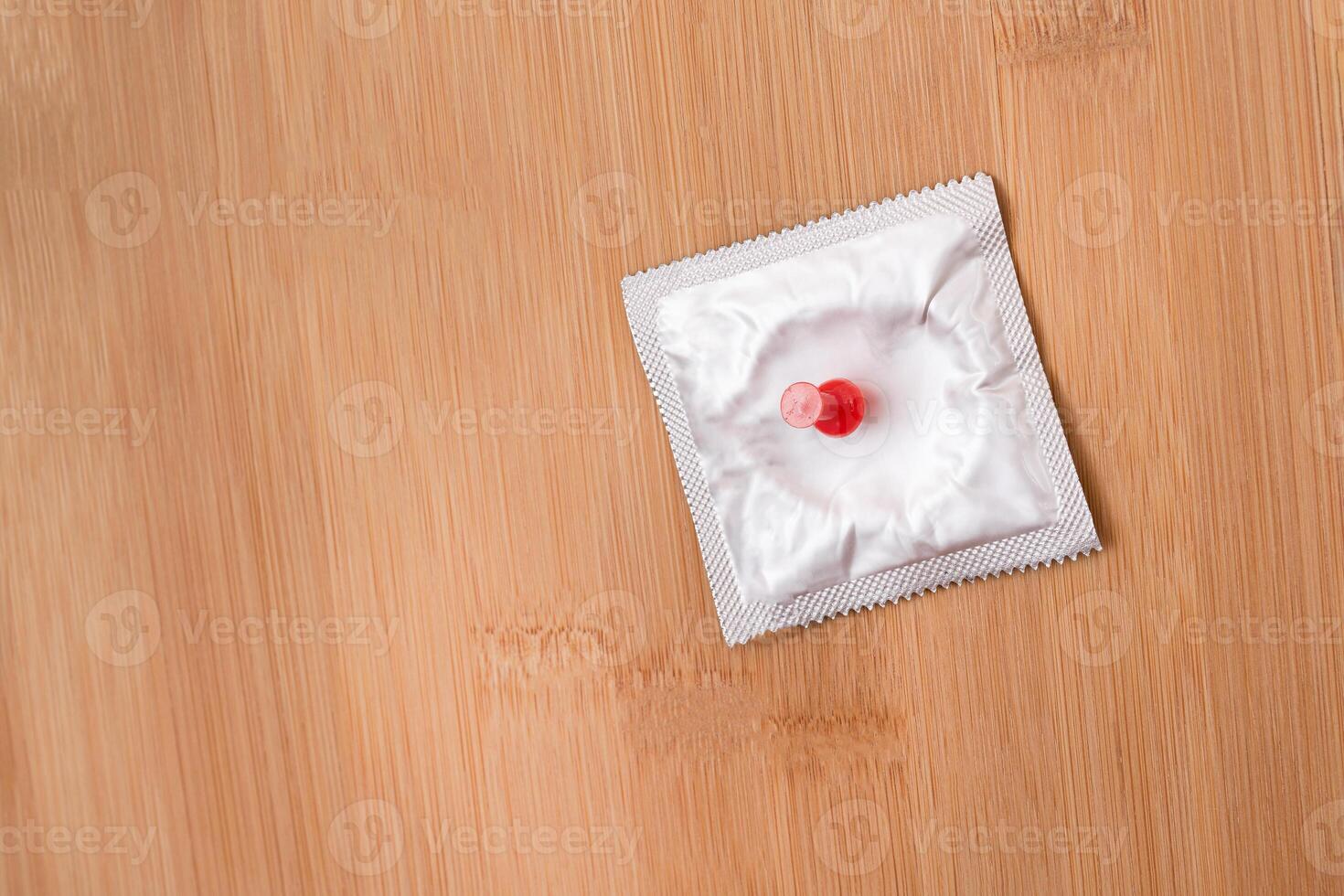 A Joke on Colleagues, Freebie or a Defective Condom - Packaged Latex Condom Pinned to a Wooden Message Board photo