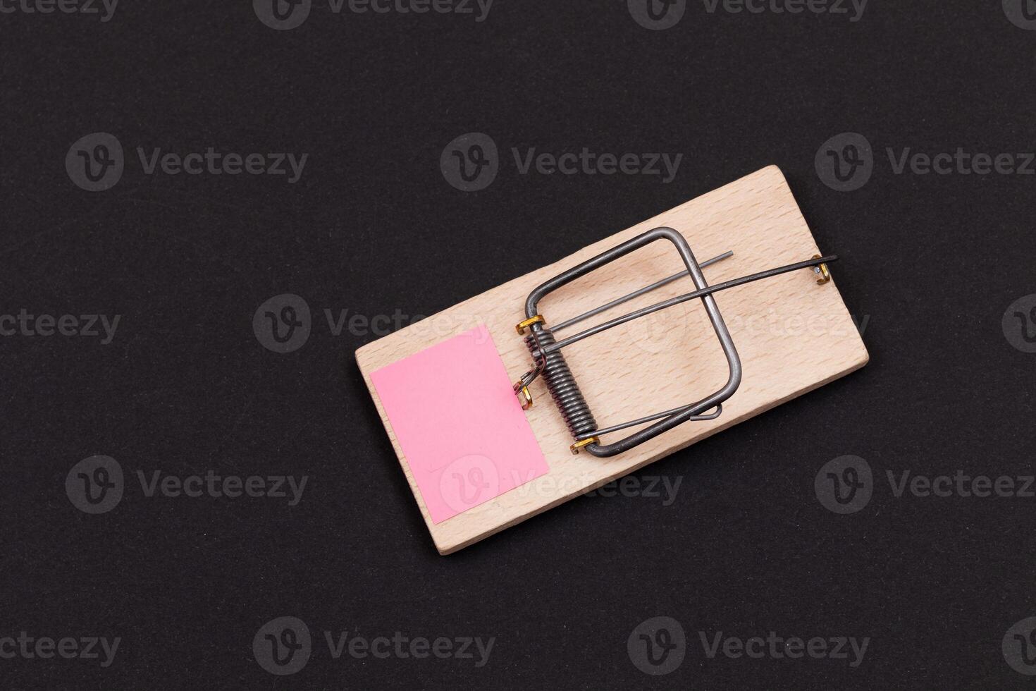 Blank Pink Sheet of Paper in Wooden Mousetrap - Template. Small Memo Paper in Mouse Trap on Black Background photo