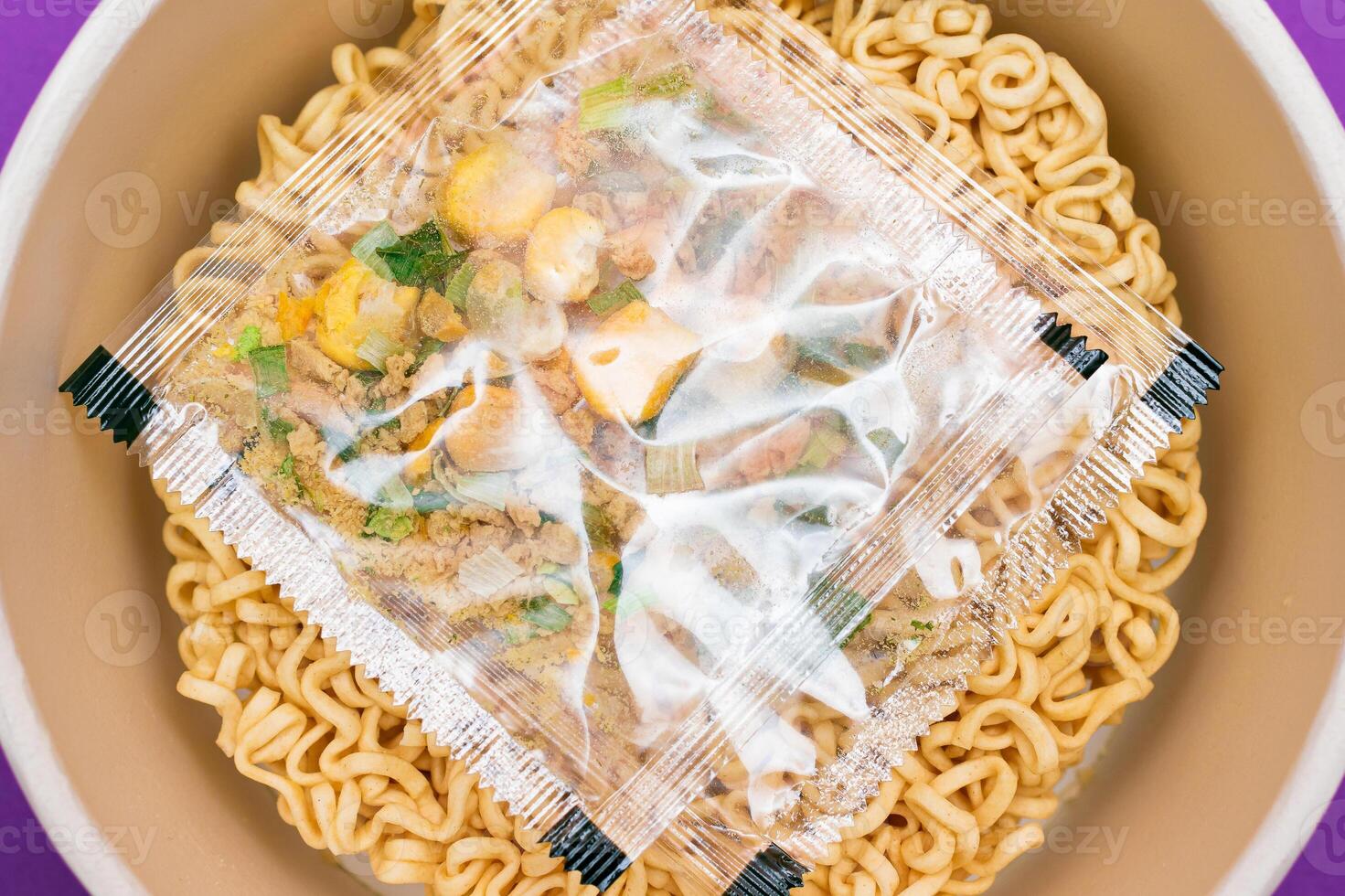 Opened Package with Uncooked Instant Noodles on Violet Background. Raw Pasta. Dry Asian Fast Food. Quick Lunch photo