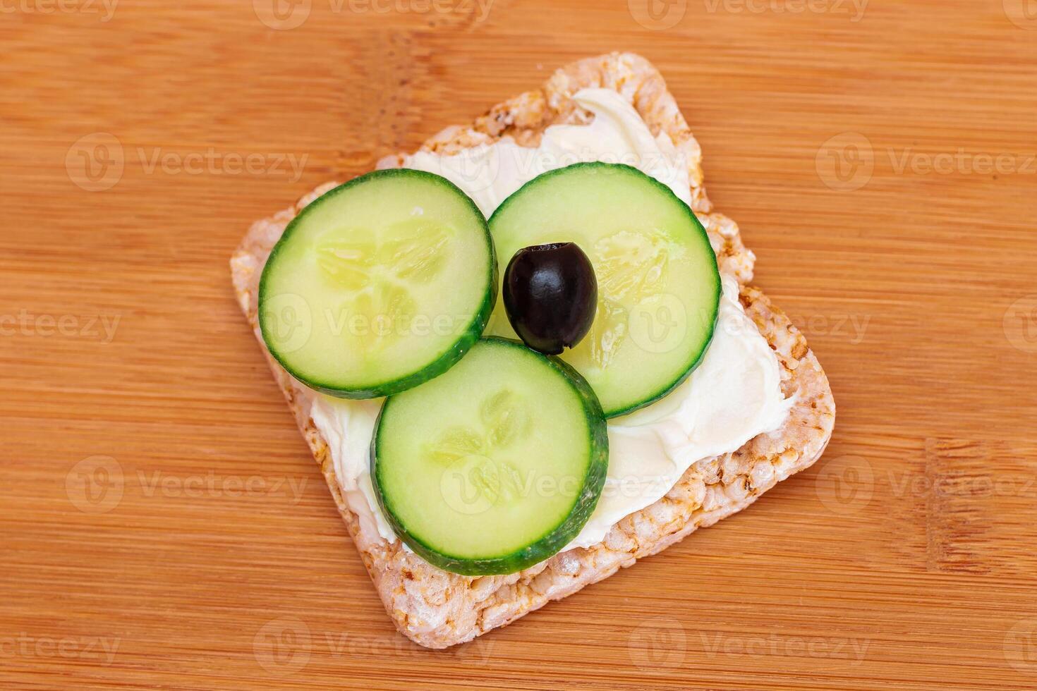 Rice Cake Sandwich with Fresh Cucumber, Cream Cheese and Olives on Bamboo Cutting Board. Easy Breakfast. Diet Food. Quick and Healthy Sandwiches. Crispbread with Tasty Filling. Healthy Dietary Snack photo