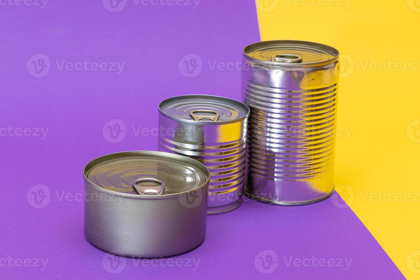 A Group of Stacked Tin Cans with Blank Edges on Split Yellow and Violet Background. Canned Food. Different Aluminum Cans for Safe and Long Term Storage of Food. Steel Sealed Food Storage Containers photo