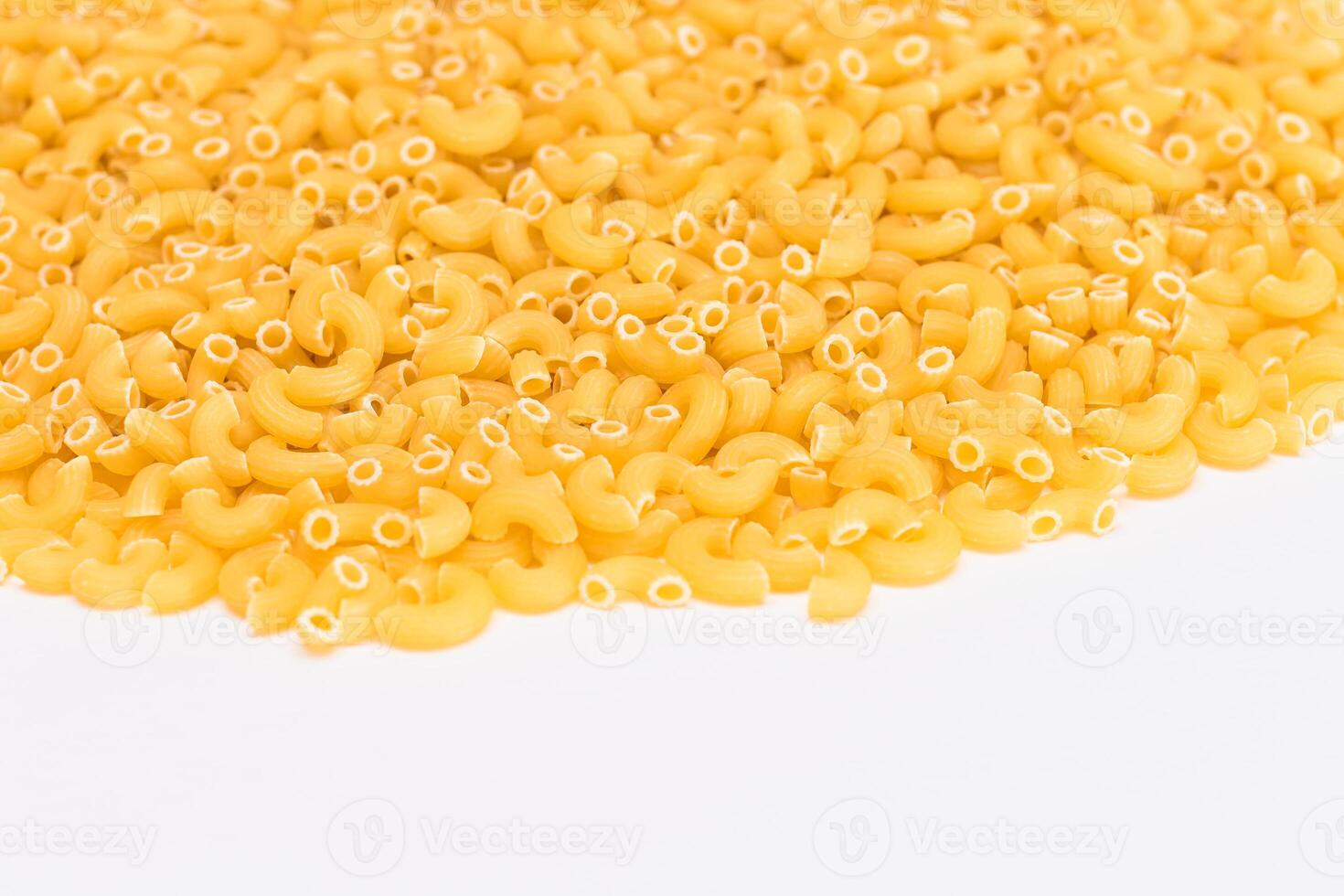 A Heap of Uncooked Chifferi Rigati Pasta on White Background. Fat and Unhealthy Food. Classic Dry Macaroni Texture. Italian Culture and Cuisine. Raw Pasta photo