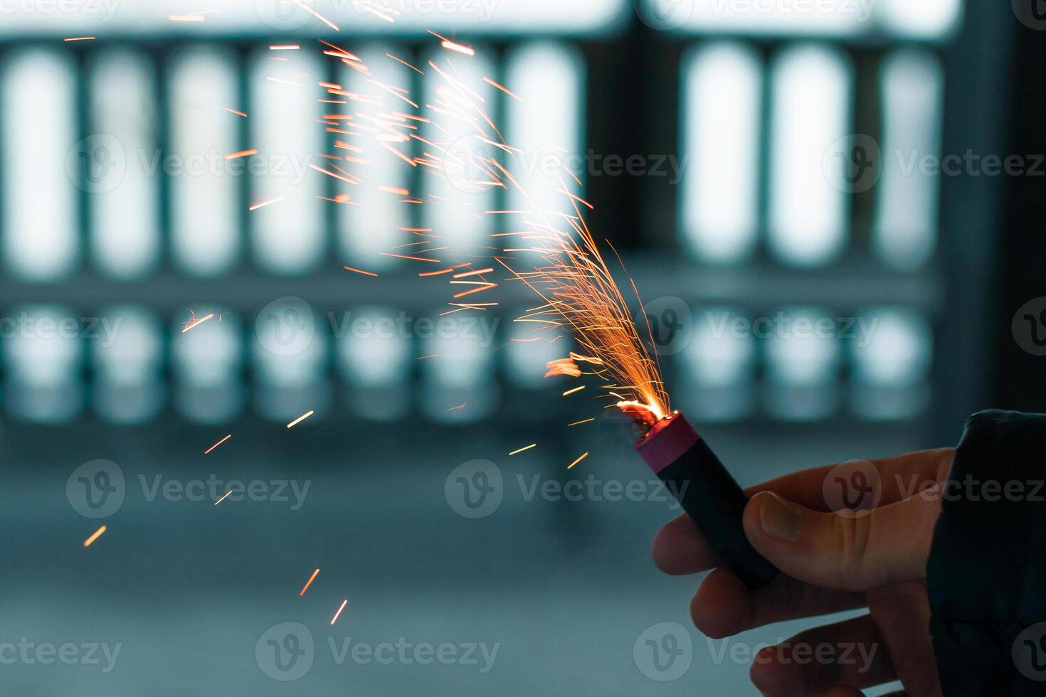 Burning Firecracker with Sparks. Guy Holding a Petard in a Hand. Loud and Dangerous New Year's Entertainment. Hooliganism with Pyrotechnics. Noise of Firecrackers in Public Places photo