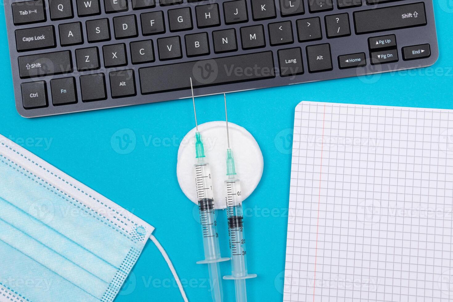 Vaccination, Immunology or Revaccination Concept - Two Medical Syringe Lying on Blue Table in Doctor's Office in a Hospital or Clinic. Opened Blank Notepad - Mock Up with Copy Space photo