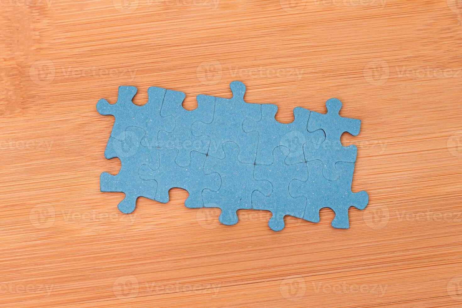 Top View of a Blue Puzzle Pieces Lie on the Wooden Table photo