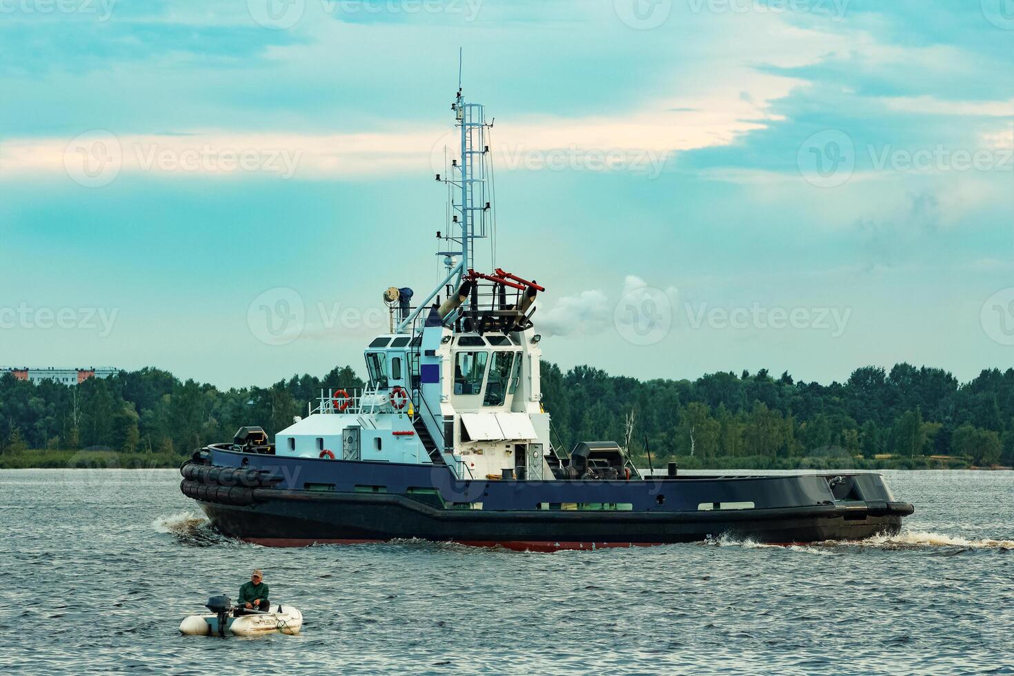 Black tug ship moving to the cargo terminal. Industrial service photo