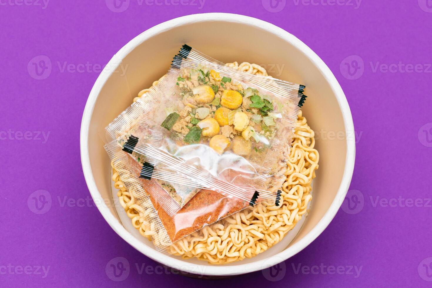 Opened Package with Uncooked Instant Noodles on Violet Background. Raw Pasta. Dry Asian Fast Food. Quick Lunch photo