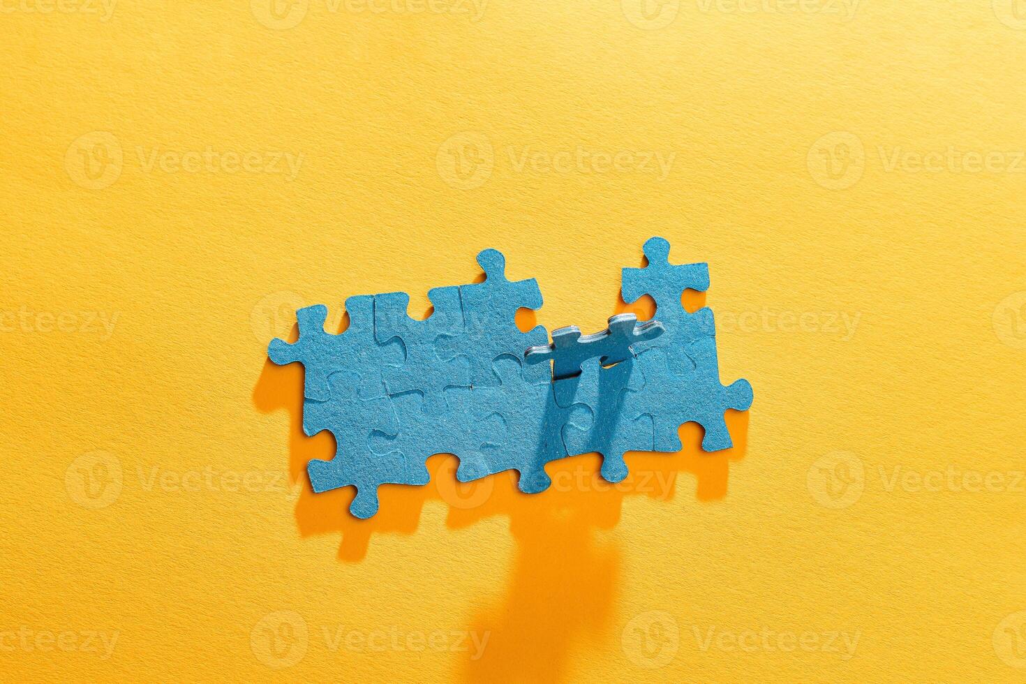 Top View of a Blue Puzzle Pieces Lie on the Yellow Background photo
