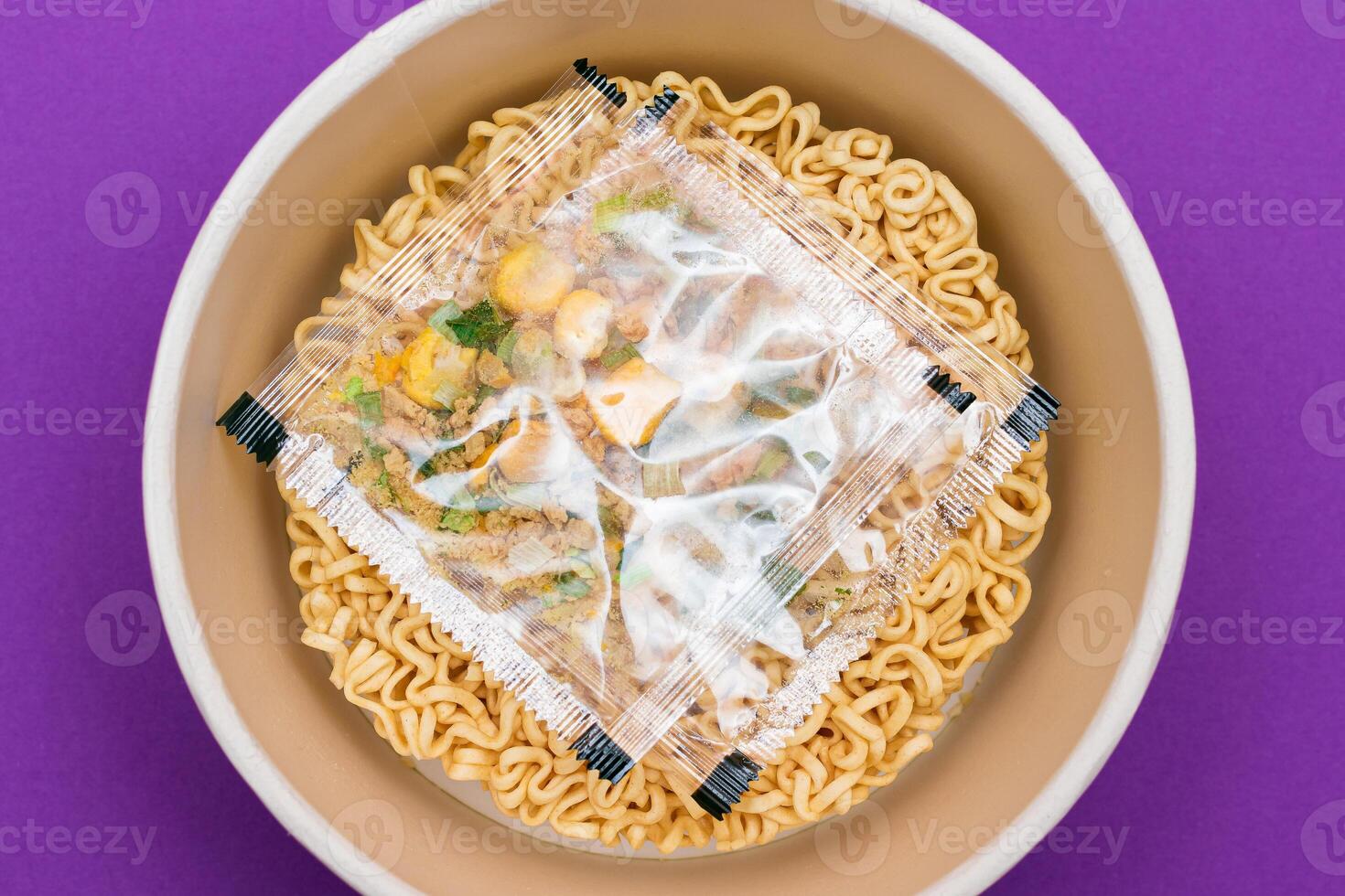 Opened Package with Uncooked Instant Noodles on Violet Background. Raw Pasta. Dry Asian Fast Food. Quick Lunch photo