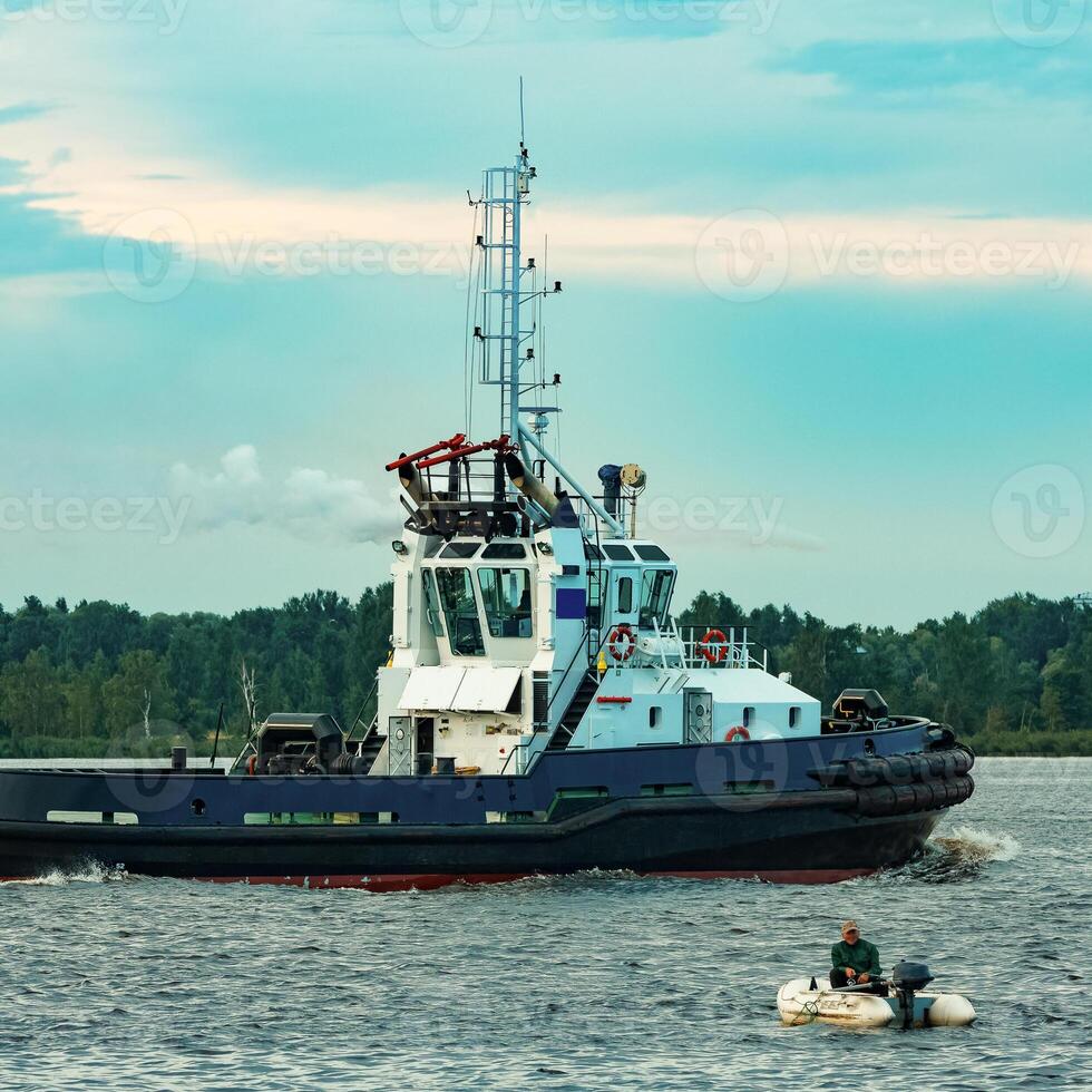 Black tug ship moving to the cargo terminal. Industrial service photo