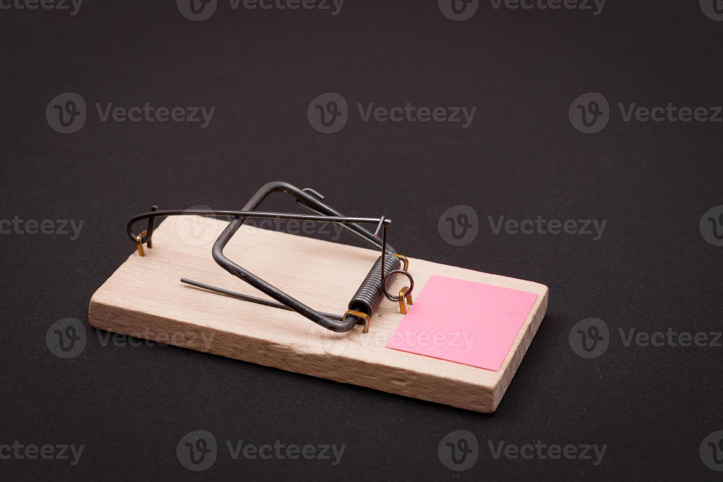 Blank Pink Sheet of Paper in Wooden Mousetrap - Template. Small Memo Paper in Mouse Trap on Black Background photo