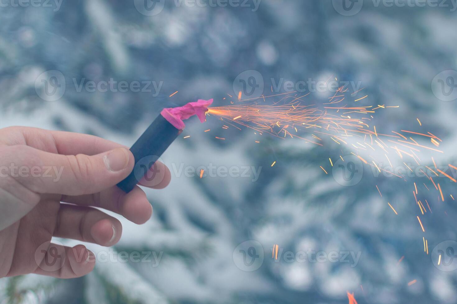 Burning Firecracker in a Hand. Guy Holding a Petard Outdoors in Winter at Daytime. Loud and Dangerous New Year's Entertainment. Hooliganism with Pyrotechnics. Noise of Firecrackers in Public Places photo