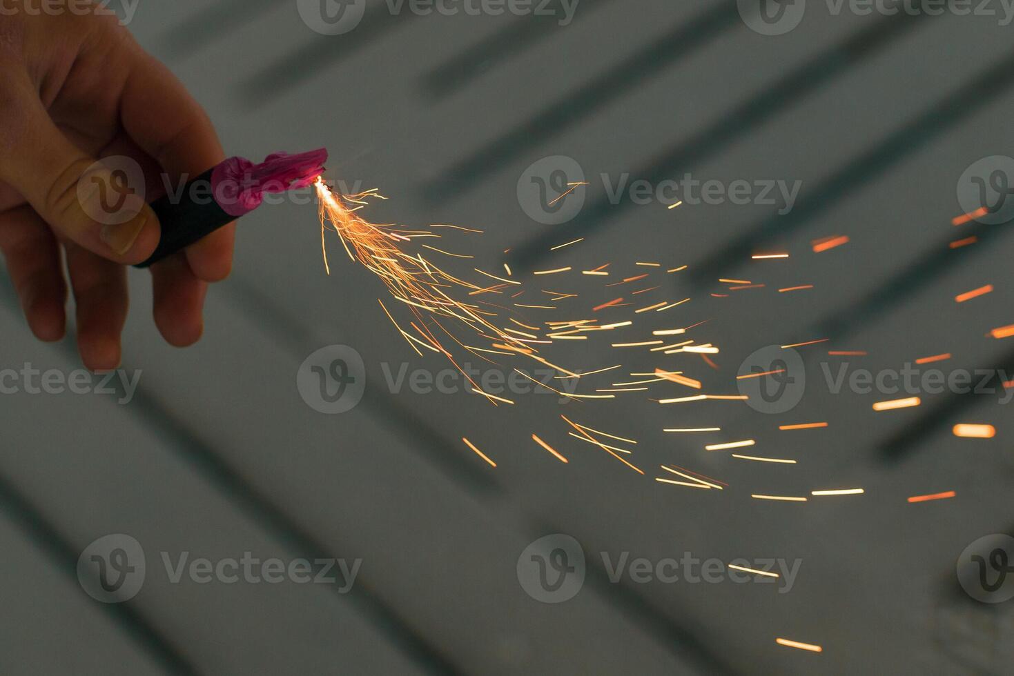 Burning Firecracker with Sparks. Guy Holding a Petard in a Hand. Loud and Dangerous New Year's Entertainment. Hooliganism with Pyrotechnics. Noise of Firecrackers in Public Places photo