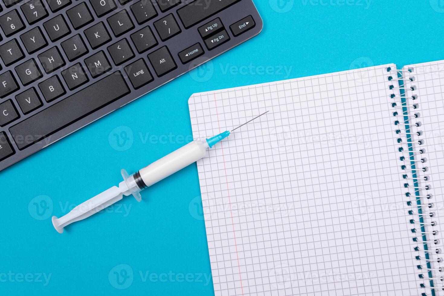 Vaccination, Immunology or Revaccination Concept - A Medical Syringe Lying on Blue Table in Doctor's Office in a Hospital or Clinic. Opened Blank Notepad - Mock Up with Copy Space photo