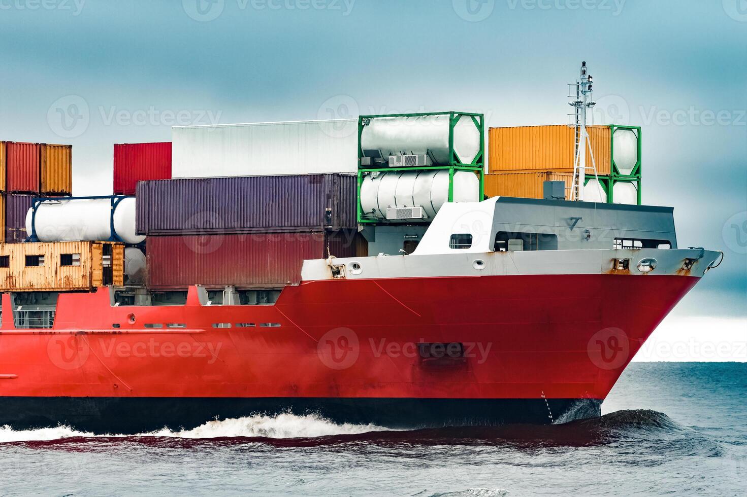 Red cargo container ship's bow in cloudy day photo