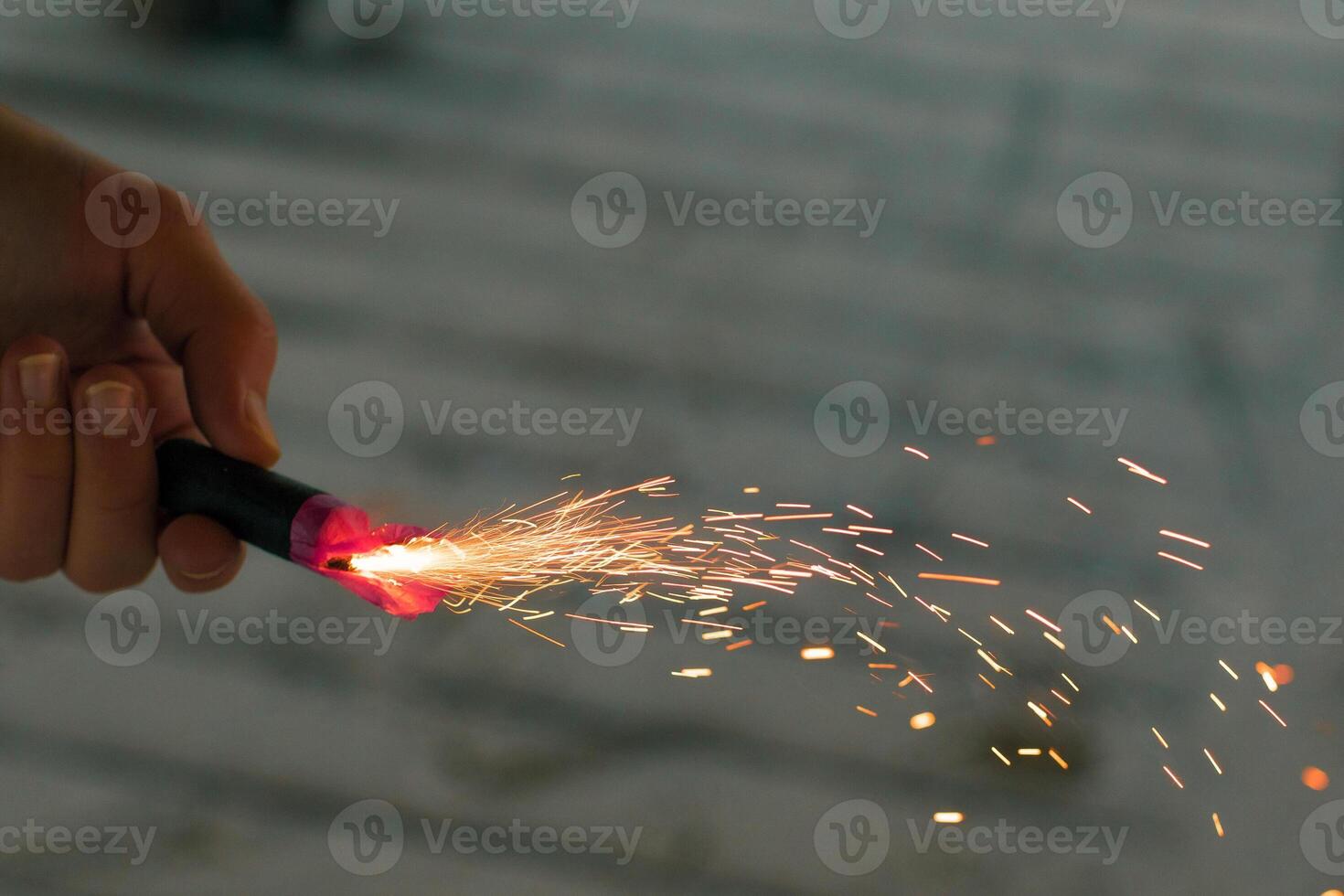Burning Firecracker with Sparks. Guy Holding a Petard in a Hand. Loud and Dangerous New Year's Entertainment. Hooliganism with Pyrotechnics. Noise of Firecrackers in Public Places photo
