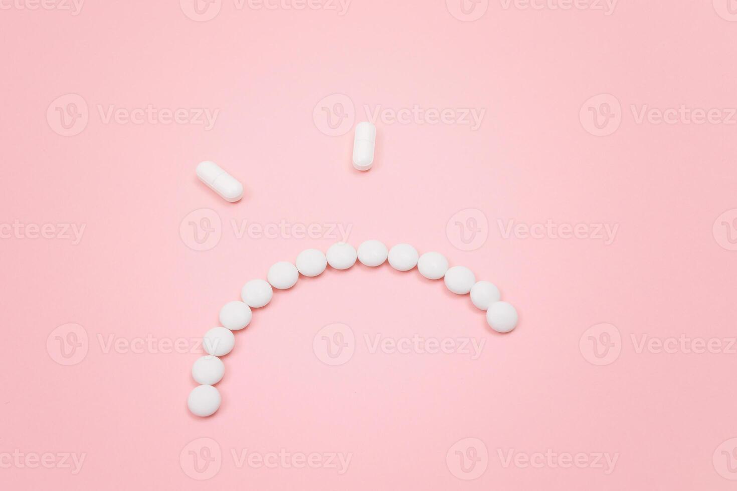 Pharma Harm. Angry Smiley Face Made from White Pills, Lying on Pink Backgrond. Global Pharmaceutical Industry and Medicinal Products photo