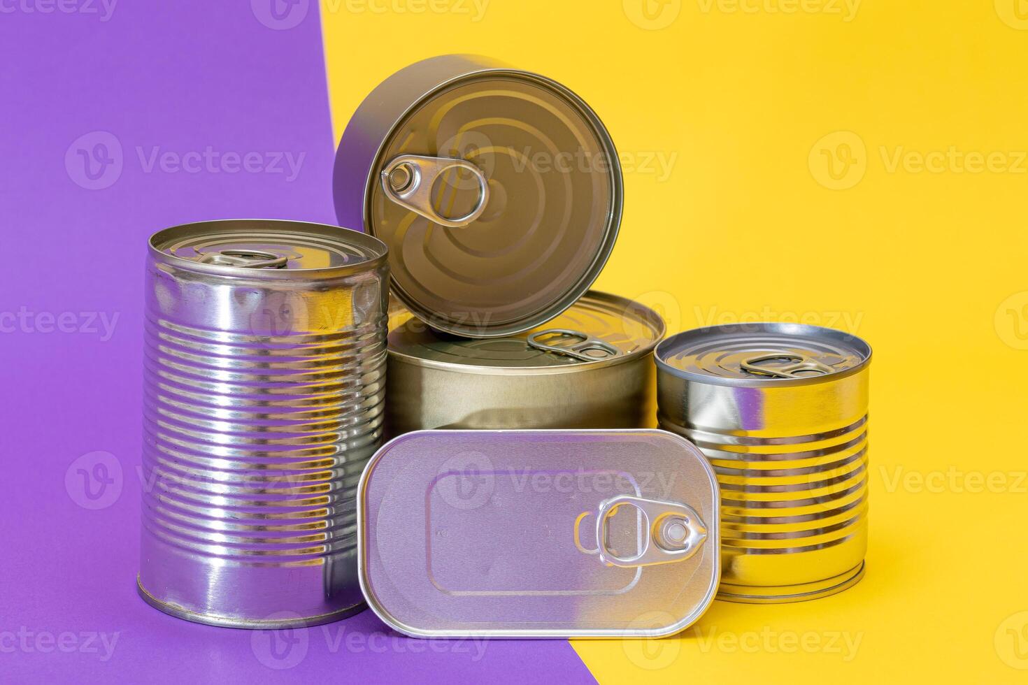 A Group of Stacked Tin Cans with Blank Edges on Split Yellow and Violet Background. Canned Food. Different Aluminum Cans for Safe and Long Term Storage of Food. Steel Sealed Food Storage Containers photo