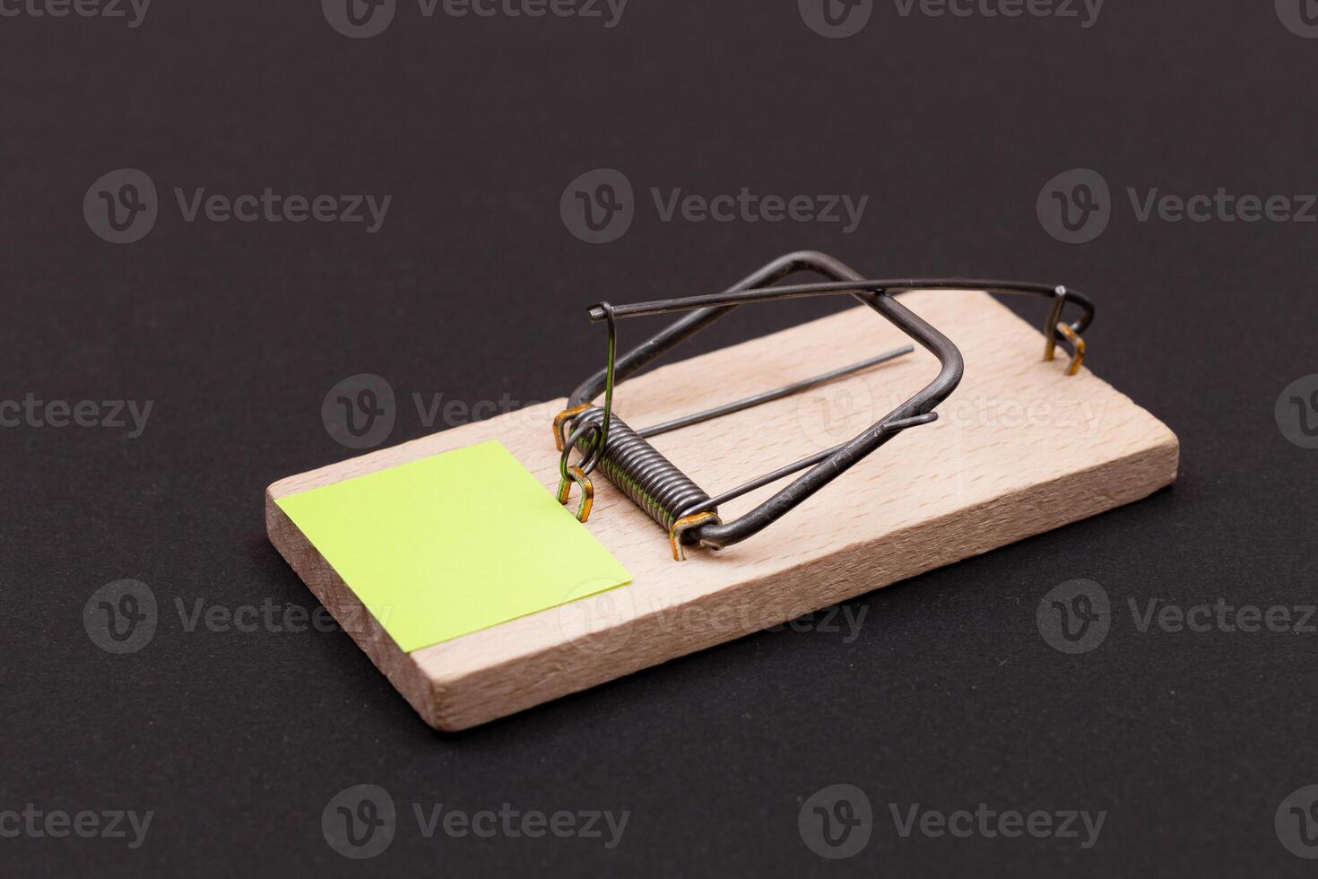 Blank Yellow Sheet of Paper in Wooden Mousetrap - Template. Small Memo Paper in Mouse Trap on Black Background photo