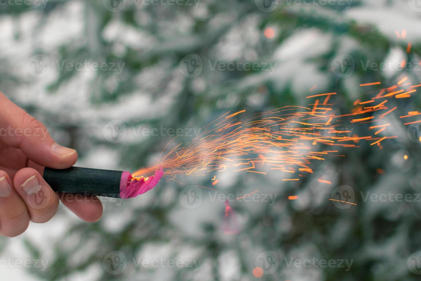 Burning Firecracker in a Hand. Guy Holding a Petard Outdoors in Winter at Daytime. Loud and Dangerous New Year's Entertainment. Hooliganism with Pyrotechnics. Noise of Firecrackers in Public Places photo