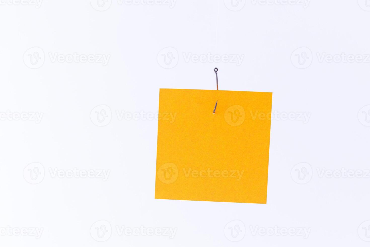 Mockup of a Blank Orange Memo Paper with Copy Space Hanging on a Fishing Hook Against the White Background. Reminder or To Do List. Sticky Note Template photo
