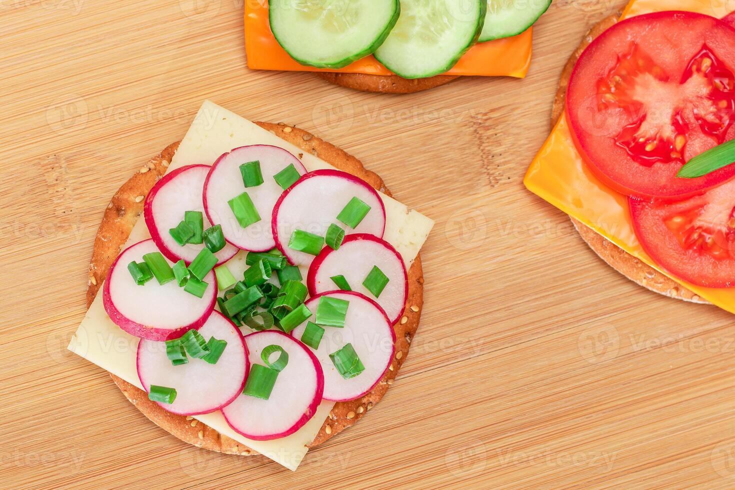 Different Cracker Sandwiches with Tomato, Cucumber, Radish and Cheese on Cutting Board. Easy Breakfast. Diet Food. Quick and Healthy Sandwiches. Crispbread with Tasty Filling. Healthy Dietary Snack photo