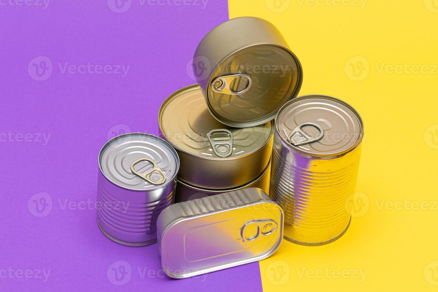 A Group of Stacked Tin Cans with Blank Edges on Split Yellow and Violet Background. Canned Food. Different Aluminum Cans for Safe and Long Term Storage of Food. Steel Sealed Food Storage Containers photo