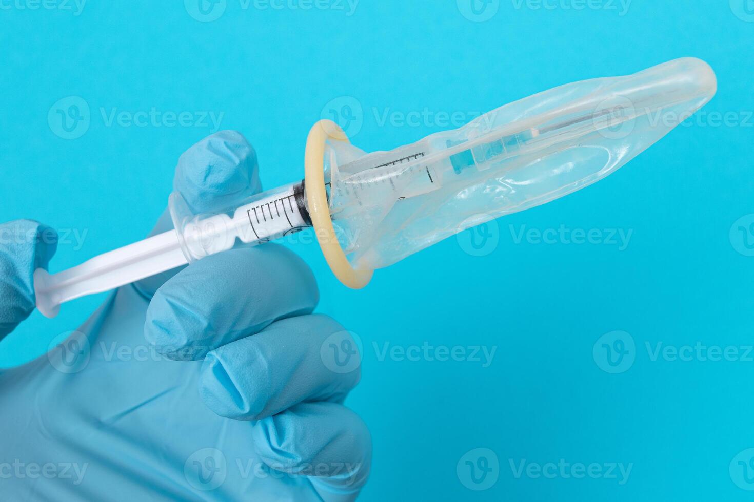 Safe Vaccine, Anti Vaccination Concept - Syringe in a Condom Holds in a Hand with Medical Glove. Mistrust of Vaccination. Natural Immunity. Skepticism About the Vaccine. Freedom and Human Rights photo
