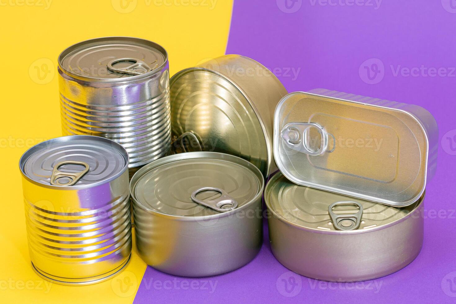 A Group of Stacked Tin Cans with Blank Edges on Split Yellow and Violet Background. Canned Food. Different Aluminum Cans for Safe and Long Term Storage of Food. Steel Sealed Food Storage Containers photo