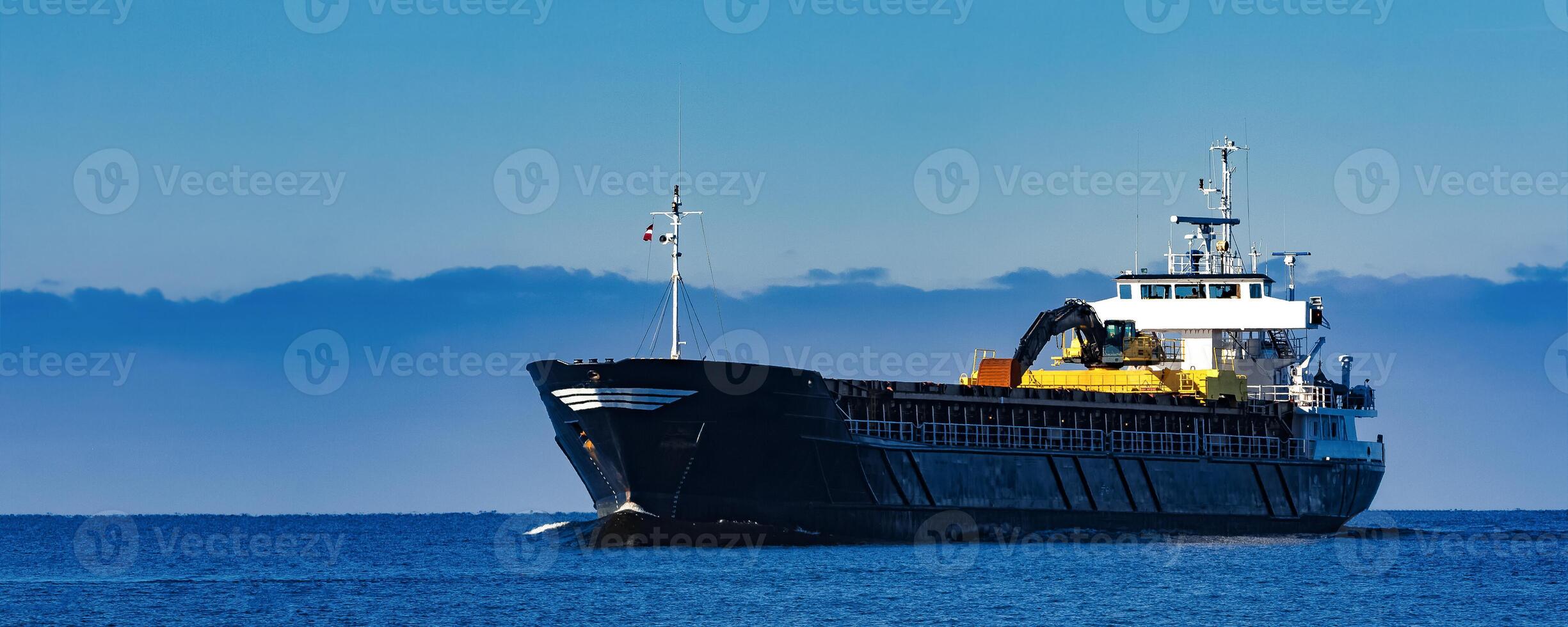 Black Sailing Bulk Carrier. Cargo Ship with Long Reach Excavator Moving in Still Water at Sunny Day by the Sea photo