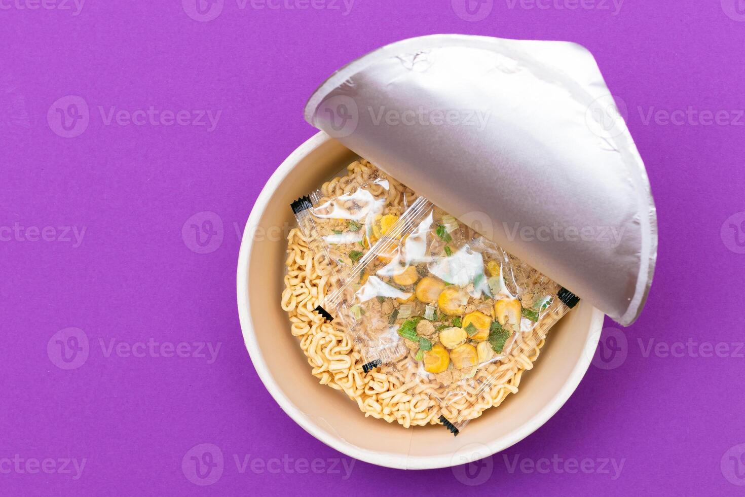 Opened Package with Uncooked Instant Noodles on Violet Background. Raw Pasta. Dry Asian Fast Food. Quick Lunch photo