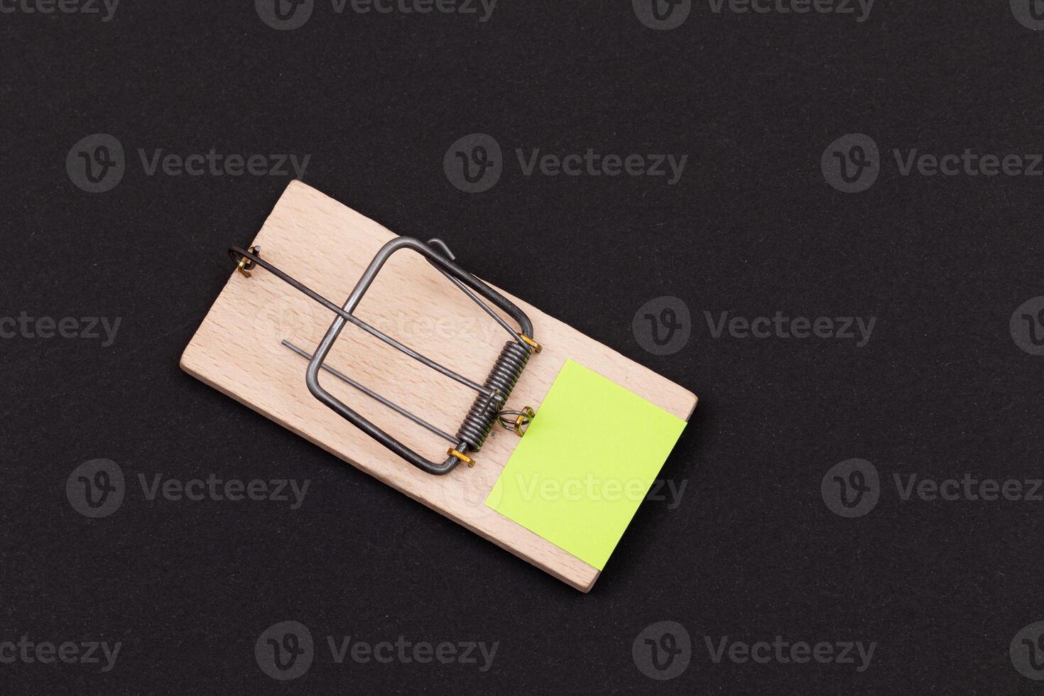 Blank Yellow Sheet of Paper in Wooden Mousetrap - Template. Small Memo Paper in Mouse Trap on Black Background photo