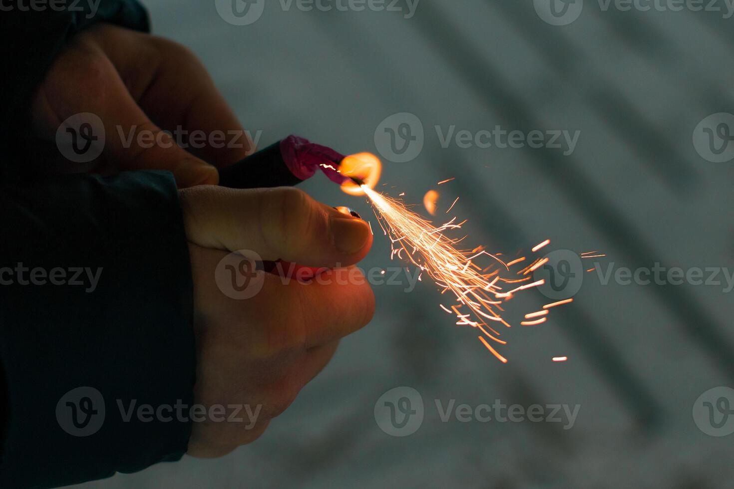 Burning Firecracker with Sparks. Guy Holding a Petard in a Hand. Loud and Dangerous New Year's Entertainment. Hooliganism with Pyrotechnics. Noise of Firecrackers in Public Places photo