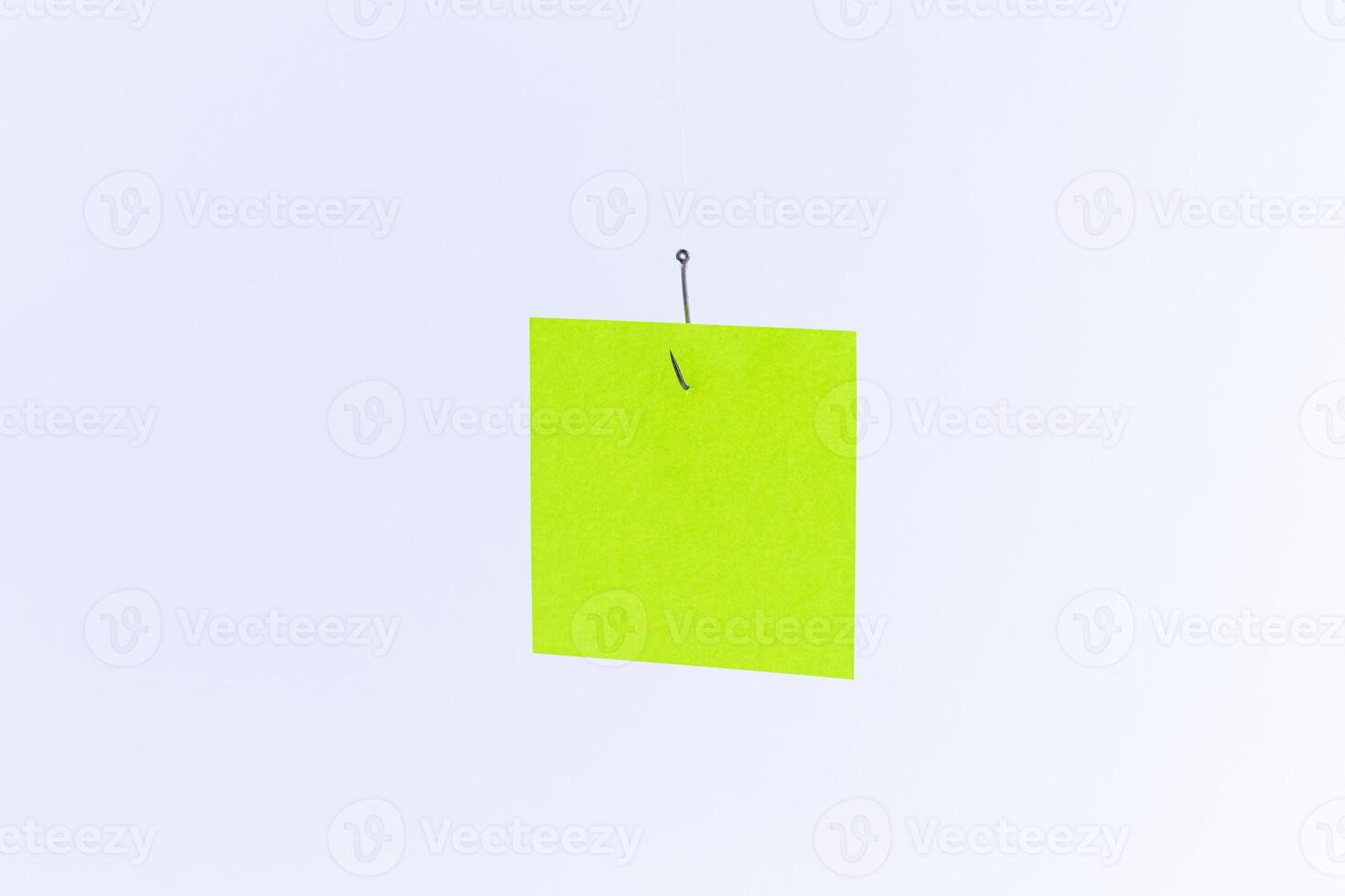 Mockup of a Blank Green Memo Paper with Copy Space Hanging on a Fishing Hook Against the White Background. Reminder or To Do List. Sticky Note Template photo