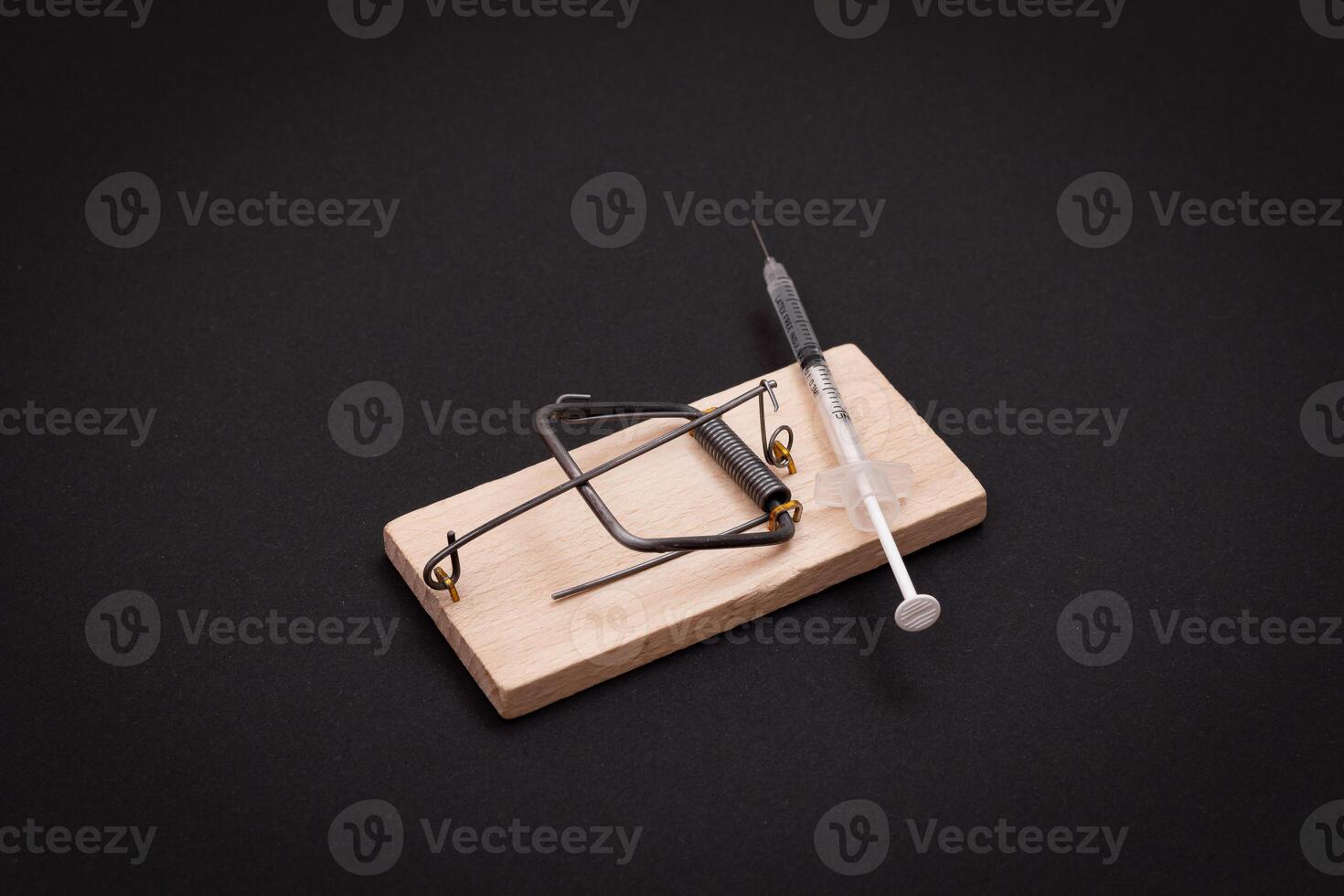 Drug Addict, Heroin Hazard or Dose Trap Concept - Disposable Insulin Syringe with Drug Dose Inside Lying in Wooden Mousetrap on Black Background photo