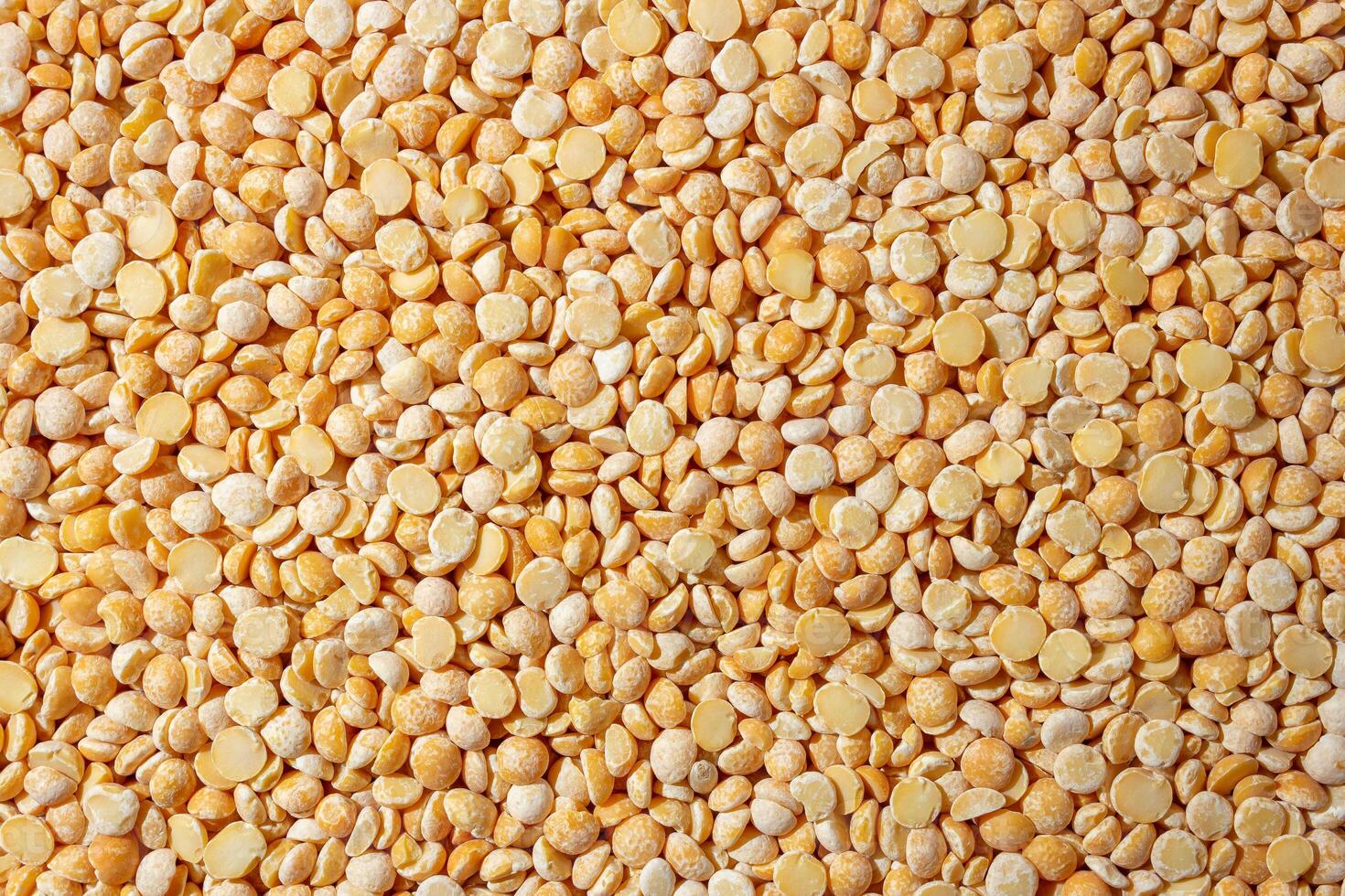 Uncooked Polished Split Peas Background. A Culinary Canvas of Dry Yellow Peas, Creating a Lively and Textured Background for Gourmet Cooking. Scattered Raw Polished Peas. Healthy Eating Ingredients photo
