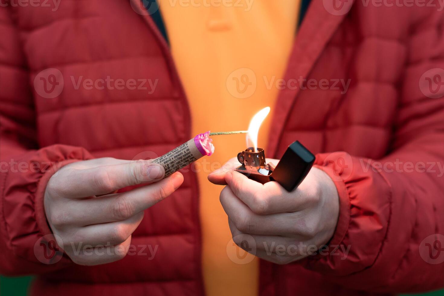 Man in Red Jacked Lighting Up Firecracker in his Hand Using Gasoline Lighter. Guy Getting Ready for New Year Fun with Fireworks or Pyrotechnic Products photo