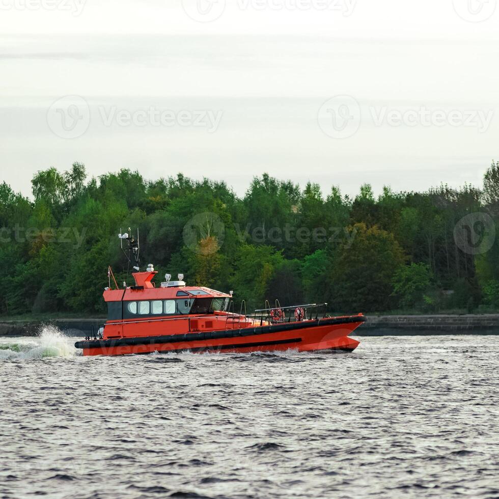 Orange pilot ship sailing on the Daugava river photo