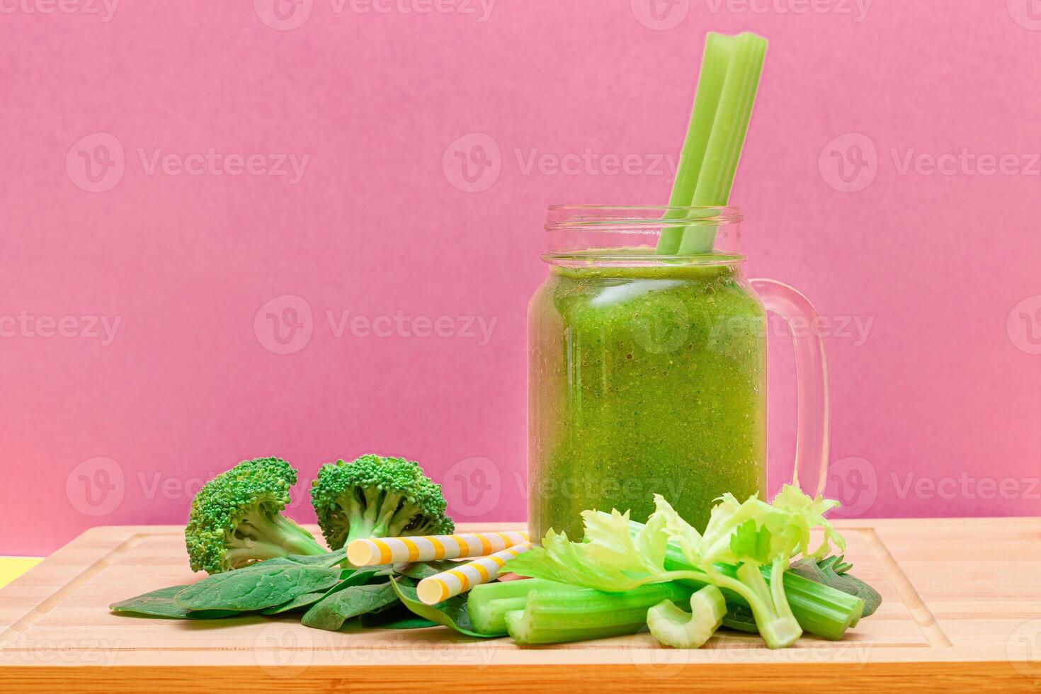Fresh Green Smoothie of Apple, Celery, and Spinach in Glass Smoothie Jar with Yellow Cocktail Straw on Wooden Cutting Board. Vegan Detox Drink. Vegetarian Culture. Healthy Eating and Fruit Diet photo