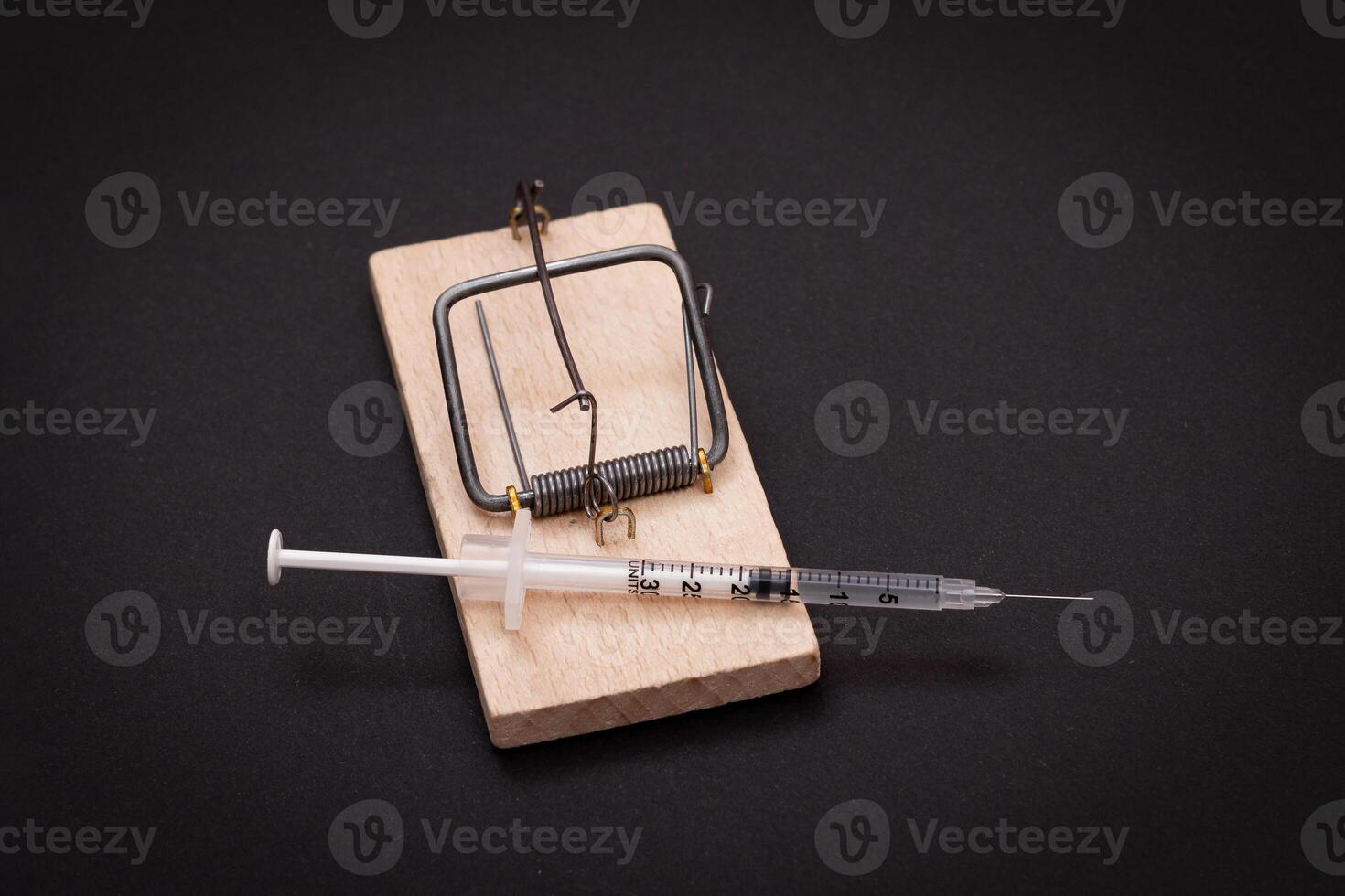 Drug Addict, Heroin Hazard or Dose Trap Concept - Disposable Insulin Syringe with Drug Dose Inside Lying in Wooden Mousetrap on Black Background photo