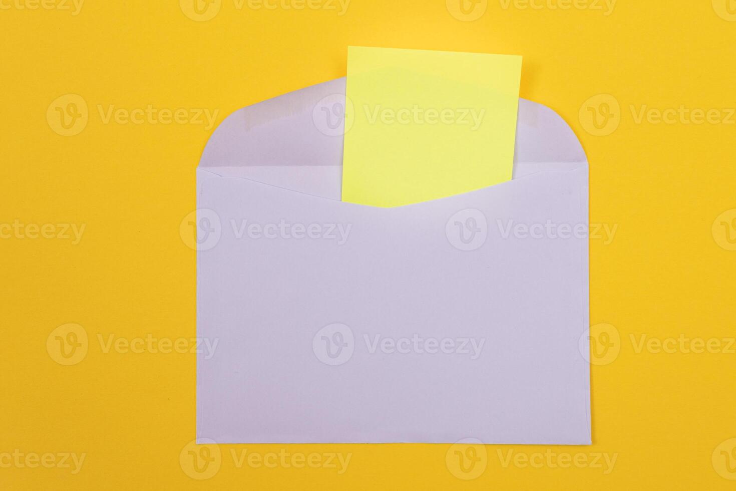Violet Envelope with Blank Yellow Sheet of Paper Inside, Lying on Yellow Background - Mock Up with Copy Space. Receiving Mail or Notice, Sending Postcard - Top View, Flat Lay photo