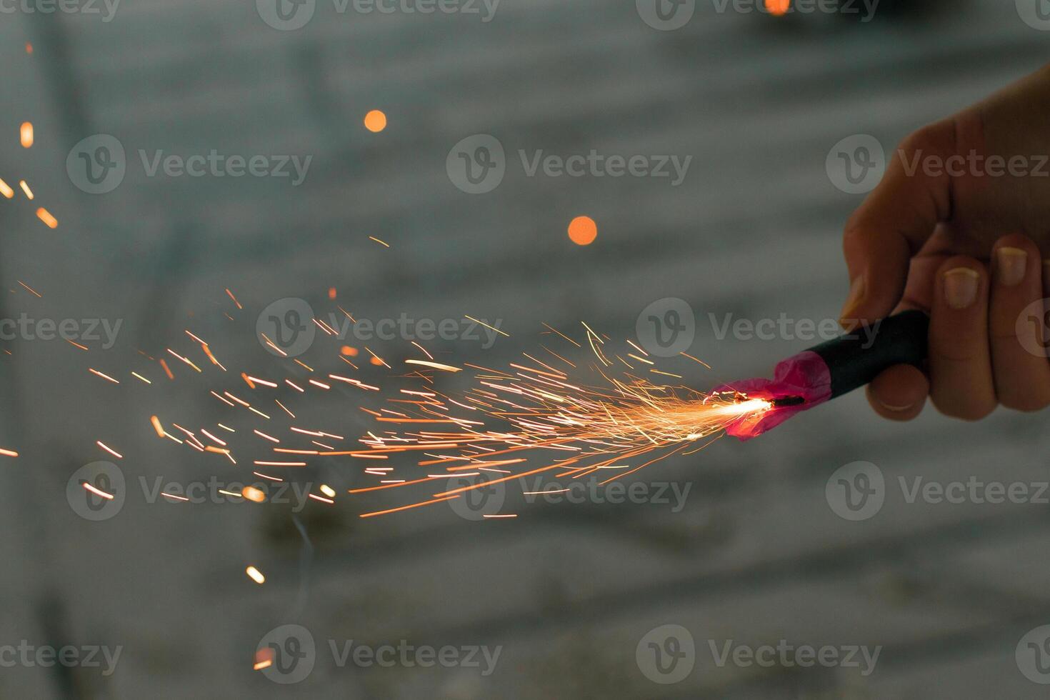 Burning Firecracker with Sparks. Guy Holding a Petard in a Hand. Loud and Dangerous New Year's Entertainment. Hooliganism with Pyrotechnics. Noise of Firecrackers in Public Places photo