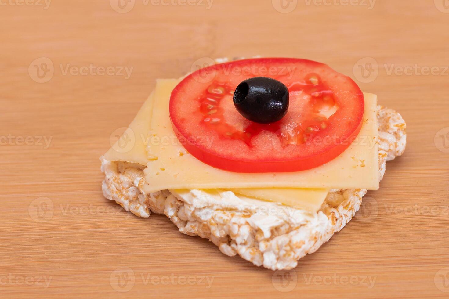 Rice Cake Sandwich with Tomato, Cheese and Olives on Bamboo Cutting Board. Easy Breakfast. Diet Food. Quick and Healthy Sandwiches. Crispbread with Tasty Filling. Healthy Dietary Snack photo